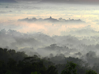 An aerial view of Borobudur Temple in a foggy and misty morning seen from Setumbu Hill using Tele Zoom lens to capture the beautiful nature and a sacred temple.