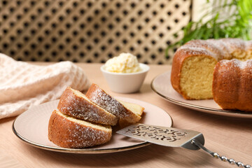 Pieces of freshly baked sponge cake, server and ice cream on wooden table, closeup