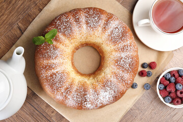 Freshly baked sponge cake, tea and berries on wooden table, top view