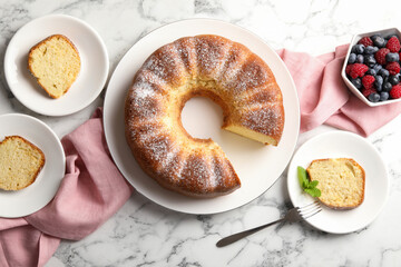 Freshly baked sponge cake, mint and berries on white marble table, top view