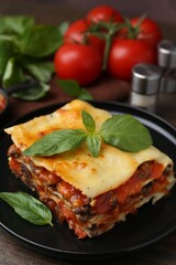 Delicious cooked lasagna with basil on wooden table, closeup