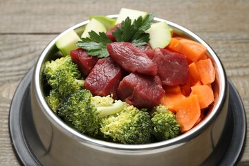 Fresh natural pet food in feeding bowl on wooden table, closeup