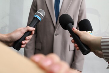 Naklejka premium Group of journalists interviewing businessman indoors, closeup