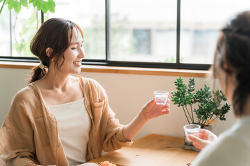 女子会で冷酒グラスで日本酒を飲む若いアジア人女性
