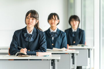 学校の教室で真剣に授業を聞く制服姿の小学生・中学生・高校生・女子高生（友達）
