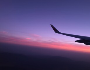 Fototapeta premium arafed view of a wing of a plane flying over a sunset