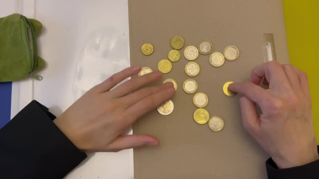 A man in a strict suit pours coins from his wallet into his hand and begins to count them carefully