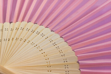 Open pink hand fan closeup. Creative concept of menopause and female hot flashes. Selective focus, place for text