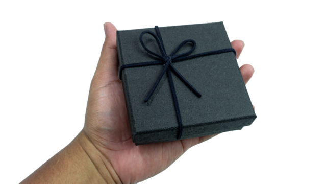 Black gift box with texture with black ribbon isolated on transparent background background. Black box being held in hand. transparent object