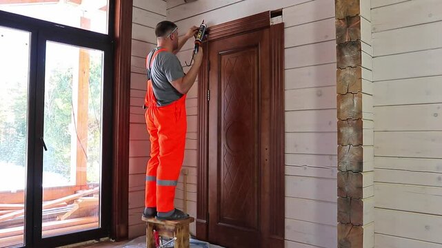 installation of door trim by professional worker in orange overalls