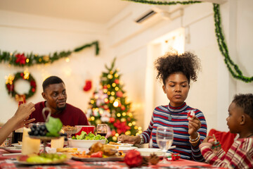 A festive family Christmas dinner setting with a decorated tree in the background. The family gathers around a beautifully decorated table, sharing food, joy, and warmth in the holiday spirit.