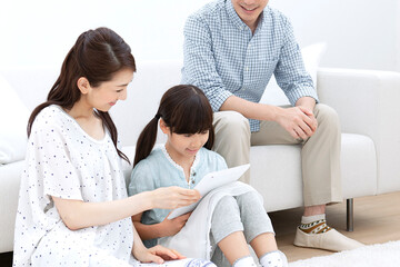 Obraz premium リビングでタブレットを操作する家族