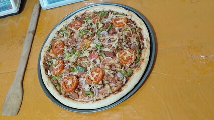 Homemade pizza with mozzarella cheese on top. Pizza with tomato, bell pepper, sausages and chicken on top. Delicious Homemade Pizza with Mozzarella Cheese, Tomato, Bell Pepper, Sausages, and Chicken
