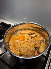 A pot noodle is cooking on the stove.