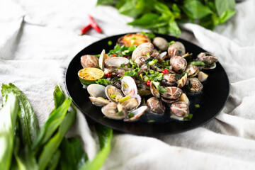 A colorful seafood dish of clams and mussels garnished with garlic and herbs on a dark plate.