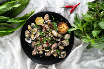 Fresh seafood featuring clams and mussels cooked with garlic, garnished with herbs and lime. Flat lay