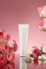 Advertising photo for pink rose cosmetic products, was taken from front view. A white cosmetic tube without label standing out on pink background, fresh pink rose featured on both sides