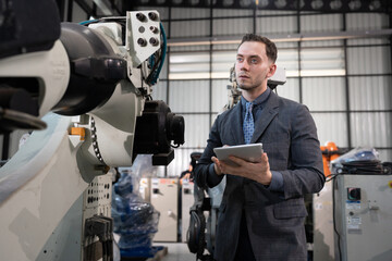 Business or engineer Caucasian male use tablet computer checking robot arm