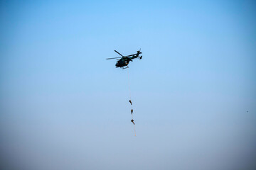 Para commandos slithering and rappelling from helicopter
