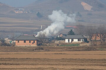 Naklejka premium A peaceful evening shot of a Hmong village with smoke rising from the chimneys and the last rays of sunlight casting long shadows