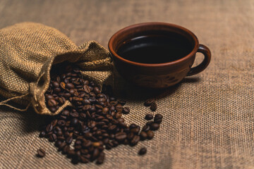 Burlap sack spilling coffee beans with a rustic cup of black coffee