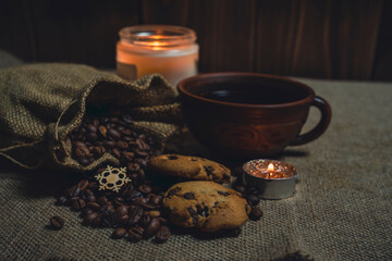 Coffee with cookies, burlap sack of beans, and glowing candles