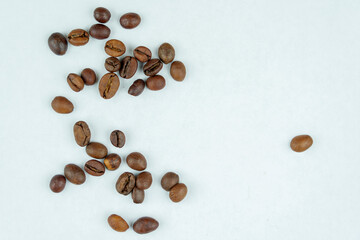 Coffee beans spread on a plain white surface
