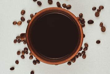 Overhead view of coffee cup with scattered beans on white background