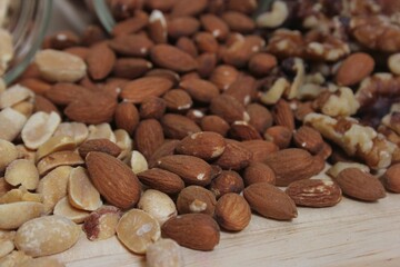 Closeup shot of various nuts scattered on a wooden table in rustic kitchen, with blurred background