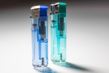 Two lighters in dark and light blue colors reflecting light on a smooth surface