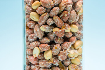 Salted peanuts filled in glass jar on blue background