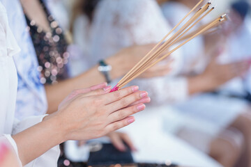 close up of hands holding incense sticks