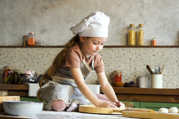 Joyful little girl sitting on counter and playing with flour, creating a playful mess while baking