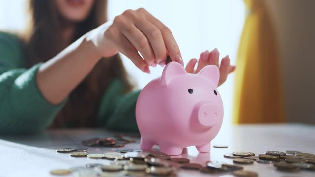 The girl puts coins into the piggy bank. the concept of saving money is saving. man puts a piggy in his hand and puts lifestyle money in a. bank. a girl puts coins in her hand in a bank.