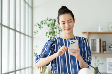 家でスマホを使う若い女性