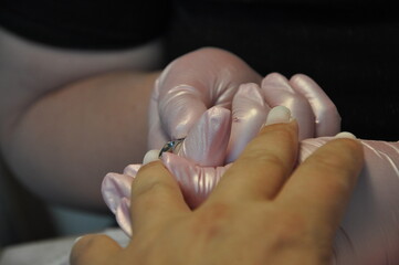 Manicurist cut the cuticle to the client. Preparing nails before manicure, trimming cuticles. Skin and nails treatment. Salon beauty and spa. Manicure, cutting skins woman to a beautician.