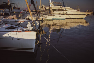 A serene marina scene in Greece during sunset, showcasing luxurious yachts and their reflections in the calm water