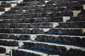 Ancient stone steps of an amphitheater in Greece, showcasing historical architecture with weathered textures and intricate craftsmanship