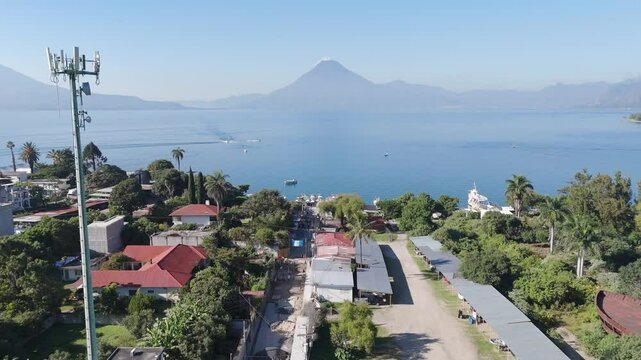 Clear view of Lago Atitlan with small docks and stunning backdrop of volcanoes under a bright blue sky