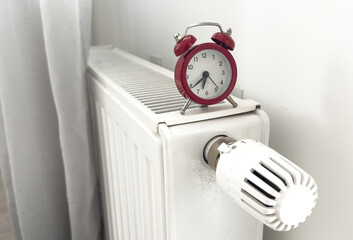 alarm clock on heating radiator against light background. Space for text.