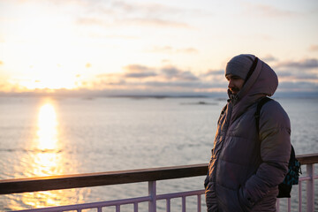 Fototapeta premium Young adult handsome man watching the sunset on a sun deck of a cruise ship