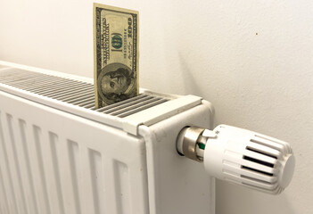 A heating radiator battery from which bills stick out. The concept of high heating expenses. Rise in energy prices, energy crisis and recession