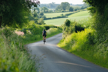 Obraz premium Cyclist Riding Through Scenic Countryside Road