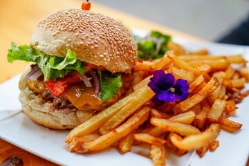 Savor the mouthwatering burger topped with melty cheese and fresh lettuce, accompanied by golden crispy fries, all served on a classic white plate at a cozy diner in the heart of New York City.