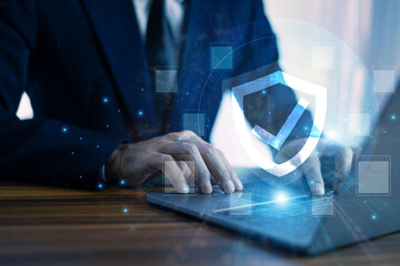 Man working on a laptop with advanced cyber security shield, ensuring the protection of sensitive data and securing the digital environment against potential threats.
