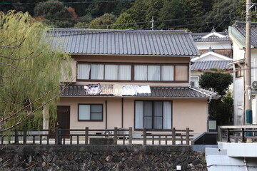 瓦屋根に布団を並べて干している２階建ての民家