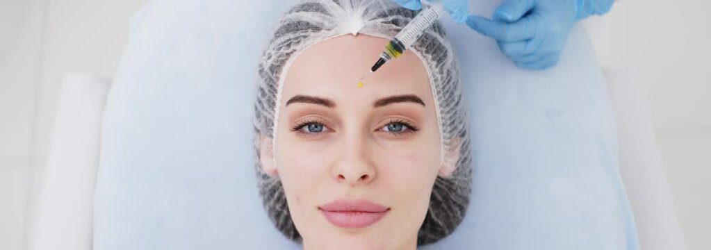 Close-up of a cosmetologist performing a facial peel on a young woman. Concept of professional care, rejuvenation, and healthy skin. Shot on anamorphic lens in 2.39