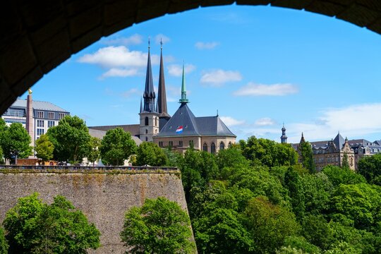 A view of the Cathedral of Notre-Dame and the fortress in the old town of Luxembourg City, Luxembourg. The buildings are made of gray stone and have intricate carvings.