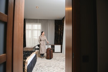 Business woman walking into hotel room with luggage