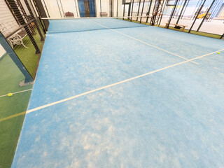 empty paddle tennis court with lights on in a covered shed with no players